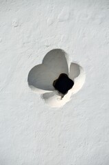 Pequeña ventana ornamentada en la pared blanca de una iglesia en Tavira, Algarve, Portugal.