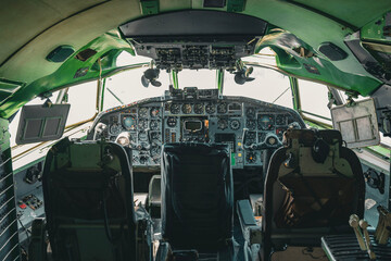 The cockpit of a Tupolev Tu-154 aircraft in detail with an extensive array of analog instruments, three crew seats, and control levers. The interior reflects the technology of a bygone era in aviation