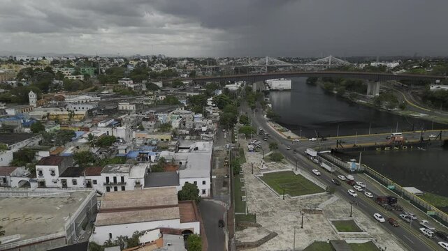 Drone flies north toward large raincloud over Ramon Matias Mella bridge in Santo Domingo, Dominican Republic