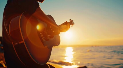 Person playing guitar at sunset by the water evoking a serene and artistic atmosphere