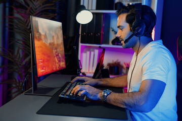 Smart gaming streamer enjoy playing battle team with streaming online shooting gun game with multi or single player at warship on pc screen, wearing headset at digital neon light cyber room. Surmise.