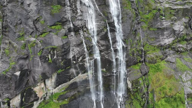 Drone closeup view of the waterfall of Vikagjolet Fossen streaming on moss-covered rocks