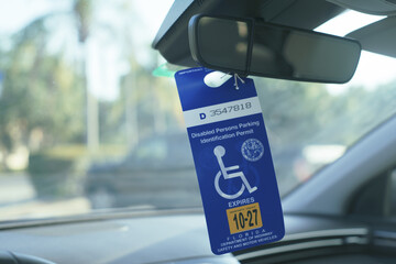 Disabled parking permit hanging from rearview mirror in car