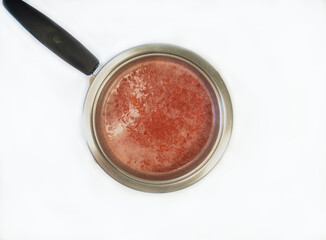 Top view of prepared strawberry mousse in a saucepan on a white background, ready for serving or use in desserts.