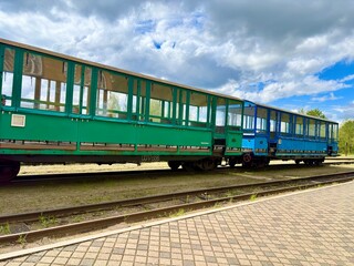 Obraz premium Colorful empty train carriages parked on railway track under cloudy sky.