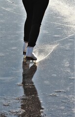 Girl learning ice-skating on frozen lake at sunset