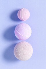 Colorful bath bombs arranged in a vertical line on a pastel-colored surface