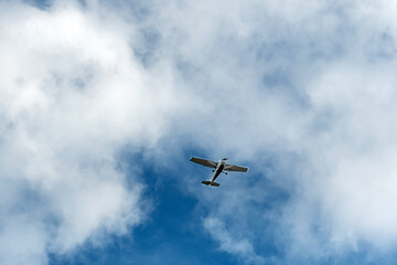Small aircraft flying across a cloudy sky at midday in an open atmosphere