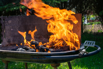 Charcoal burning in a grill with visible orange flames and black coals, high heat for barbecue...