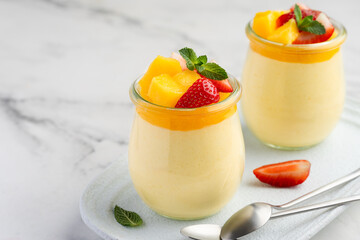 Mango mousse in jars decorated with strawberries, mango pieces and mint. Dessert made from fresh...