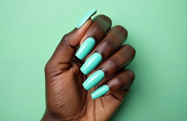 African American female hand with long, turquoise color manicure on green background. Elegant, fashionable nail art. Black skin with stylish nails. Perfect for beauty, cosmetic, salon, nail artist