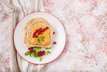 Whole grain sandwich with peanut butter and red currant top view with copy space