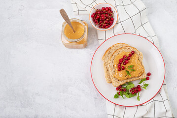 Whole grain sandwich with peanut butter and red currant berries top view on light background with copy space