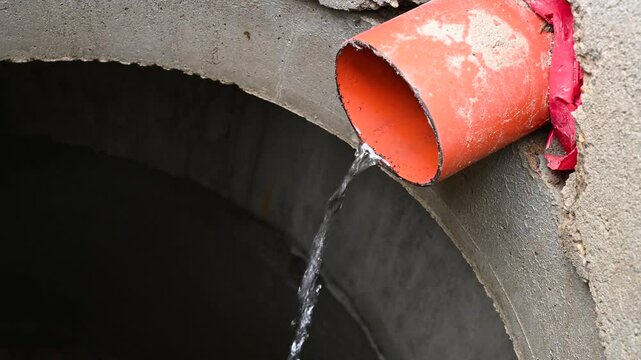 A sewer pipe for draining dirty water. A domestic sewer system. Water runs from the pipe into a well underground.