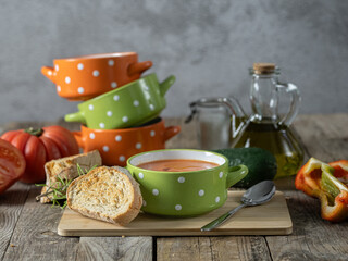 horizontal photo of a cheerful bowl of gazpacho accompanied by the ingredients to prepare it.