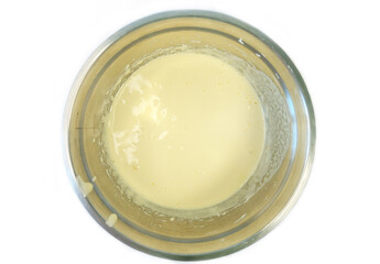 Top view of whipped eggs and sugar in a stainless steel mixing bowl, blended with a hand mixer,...