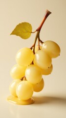 Yellow grapes with a green leaf rest on a creamy surface, showcasing a fresh and vibrant presentation