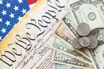 American US dollars money bills with coins and constitution close up on american flag