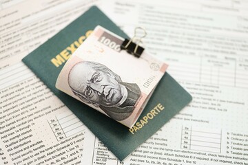 Mexican pesos money bills in big amount lies on table with passport and tax forms close up