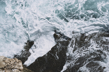 Obraz premium Dynamic ocean waves crashing over rugged coastal rocks with white foam