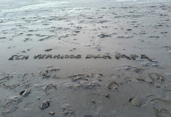 Lettering on the beach in the sand with I miss you dad