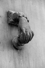Vintage bronze doorknocker with hand shape on old wooden door