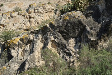 Rugged rocky landscape with green vegetation and sunlit natural terrain