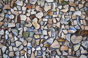 Colorful collection of ceramic fragments arranged in mosaic pattern displaying vintage designs