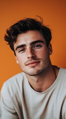 Obraz premium A Handsome Man Portrayed in a Studio Portrait with an Intense and Charming Expression in Front of Orange Wall