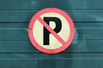 Vergilbtes rundes Verkehrsschild mit Parkverbot an dem alten grünen Garagentor mit Patina in den...