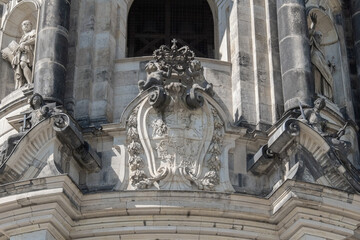 Close-up of a decorative element of the old Baroque stone facade: a carved coat of arms with a crown and gargoyle gutters.