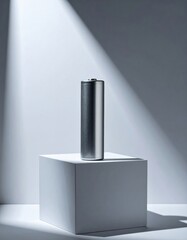 Minimalist metal cylinder displayed on geometric white pedestal in dramatic lighting