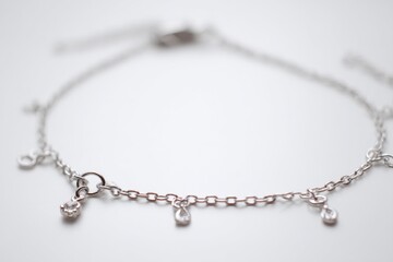 Fototapeta premium Delicate silver anklet with small charms, perfect for summer.