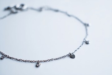 Fototapeta premium Delicate silver anklet adorned with small sparkling stones and a heart charm.