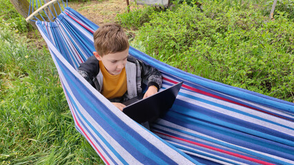 Boy relaxing on picnic during school holidays, family outdoor recreation, camping, summer school holidays. Online learning during holidays