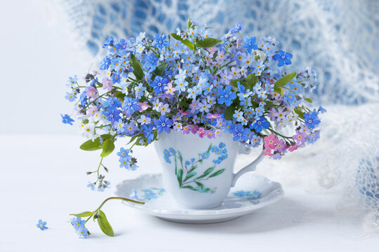 Bouquet of spring flowers forget-me-nots and omphalodes close-up in a cup on the table , blur, beautiful card