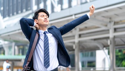 仕事終わりに伸び・ストレッチをするスーツ姿の若いアジア人男性ビジネスマン
