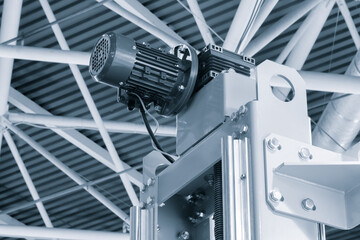 A machine with a motor on top of it. The motor is connected to a cable. The machine is in a large...