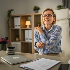 Mature woman have a shoulder pain at office