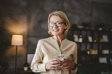Portrait of one adult mature woman hold glass of water at home