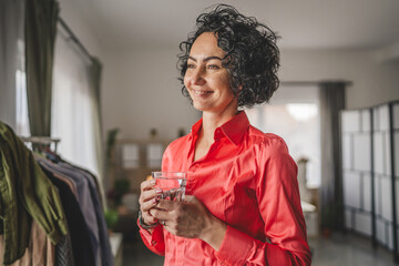 Portrait of one adult mature woman hold glass of water at home