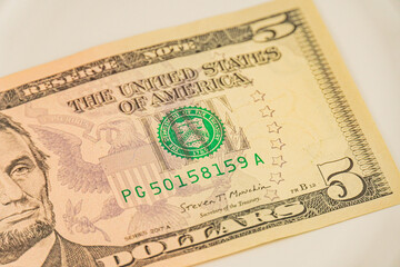 A US five-dollar note featuring Abraham Lincoln The text United States of America is visible on it