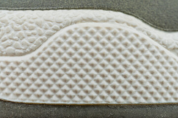 Close-up of a high-top sneaker with circular cutouts in the sole for durability and comfort, showcasing advanced design and structure