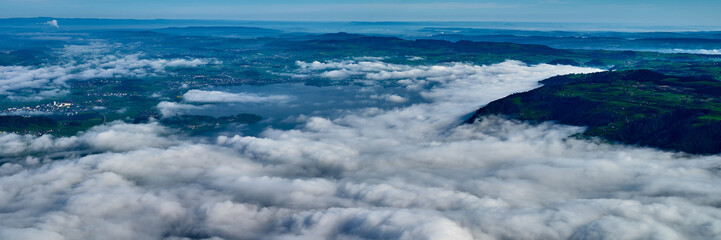 Cloudscape view over a valley with mountains and a lake during a clear day