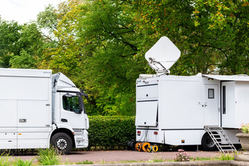 Many modern white mobile digital electric tv broadcasting trucks satellite antenna live streaming...