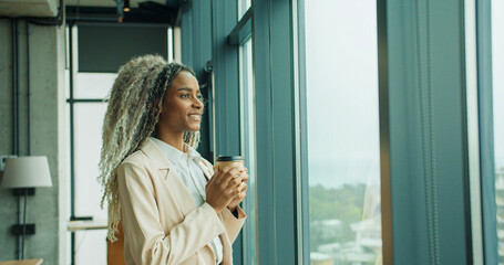 Fototapeta premium Businesswoman holding coffee while looking outside