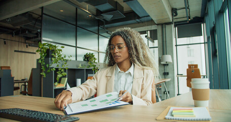 Businesswoman reviews analytics at office desk © Nataliia
