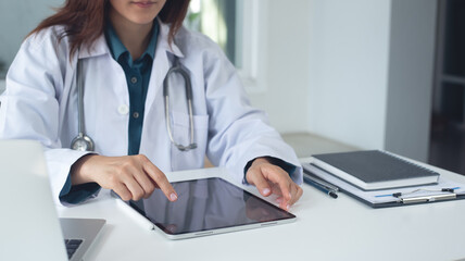 Female doctor using digital tablet, working at docotr office, searching the patient health...