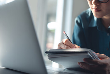 Student studying, attending online via laptop and writing note on paper notebook. Young smart business woman working on laptop computer, searching the ideas and taking note, business plan, e-learning
