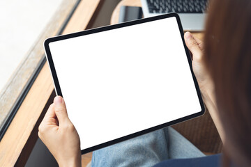 Mockup blank screen digital tablet. Woman holding digital tablet with laptop computer on table, template for web app design or social media marketing